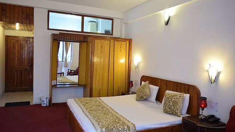 A room at DLS Hotel Devlok, Manali with a double bed and night lamps attached to the wall behind it