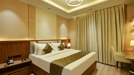 A double bed placed in the Deluxe Room with wooden flooring at Hotel 91 Privé, Gurugram, along with a workstation in the corner.