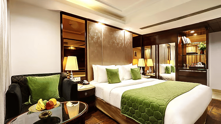 A stylish bedroom featuring a vibrant green bed runner and matching cushions, paired with elegant bedside lamps and dark wood furniture - Flute Boutique By Hotel 91, Jaipur