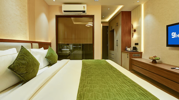 Side angle view of the Executive Room at Hotel 91 Privé, Gurugram, featuring a neatly kept double bed along with the bathroom separated by a glass partition at the far end.