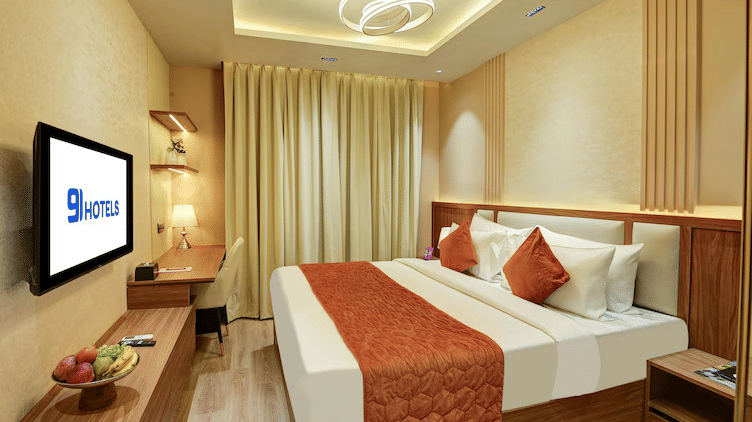 Full view of the Standard Room at Hotel 91 Privé, Gurugram, featuring a double bed and a modern light fixture hanging from the ceiling above at Hotel 91 City Centre, Gurugram.