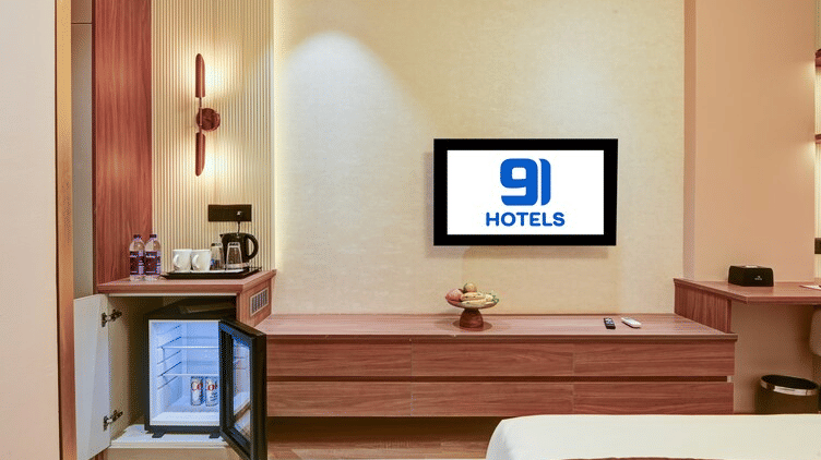 An open mini fridge alongside the TV table in the Suite of Hotel 91 Privé, Gurugram.