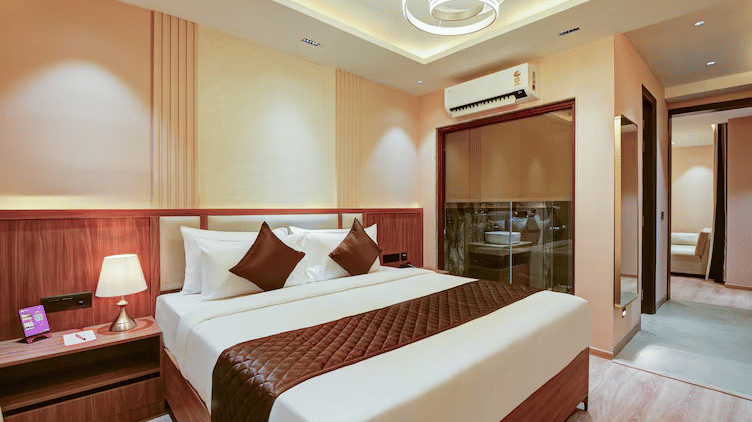 Side-angle shot of the Suite featuring a plush double bed along with a pathway crossing the bathroom door leading to the separate living area at Hotel 91 Privé, Gurugram.