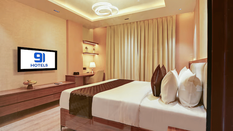 Corner shot of the Suite at Hotel 91 Privé, Gurugram, featuring a comfortable double bed placed in front of a wall-mounted TV.