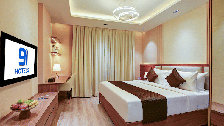 Full view of the bedroom of the Suite at Hotel 91 Privé, Gurugram, with the blackout curtains covering the window, featuring a double bed along with a wall-mounted television.