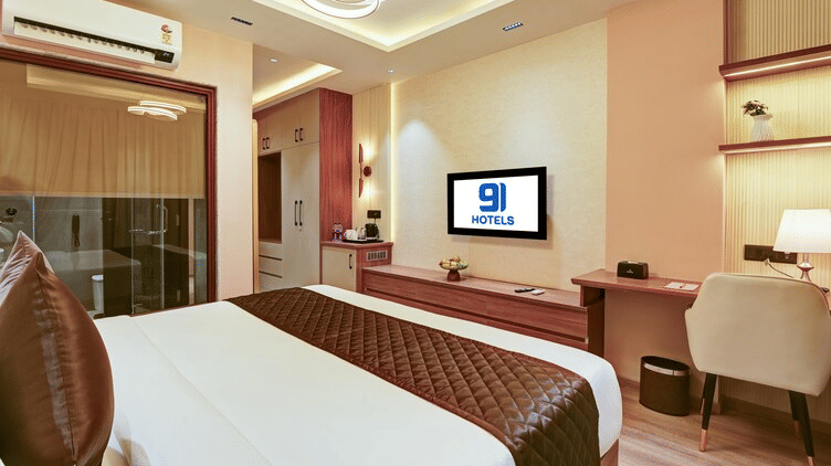An overhead shot of the bedroom of the Suite at Hotel 91 Privé, Gurugram, showcasing the work station, a wall-mounted TV, and a double bed.