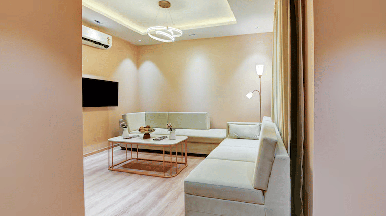 The separate living area of the Suite at Hotel 91 Privé, Gurugram, featuring warm and chic interiors with an L-shaped sofa.