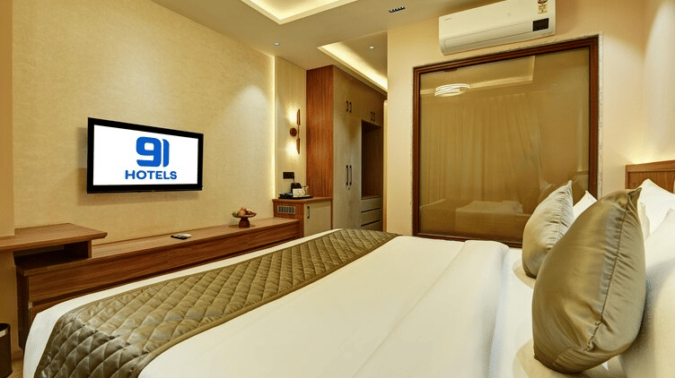 An overhead shot of the double bed facing the wall-mounted television at Hotel 91 Privé, Gurugram, in the Deluxe Room.