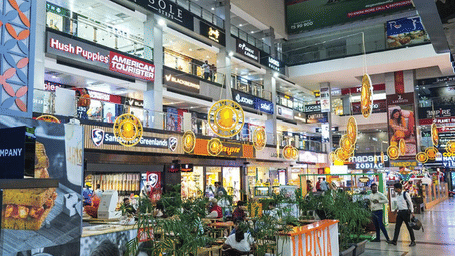 Indoor shopping mall atrium in Gurgaon featuring multiple retail outlets, signage displays, and seating areas across levels.
