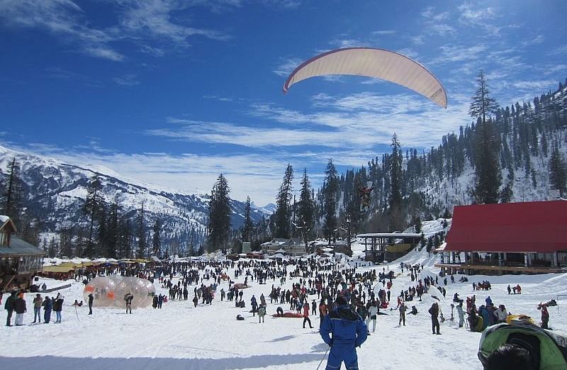 Image of Solang Valley filled with people and a man paragliding