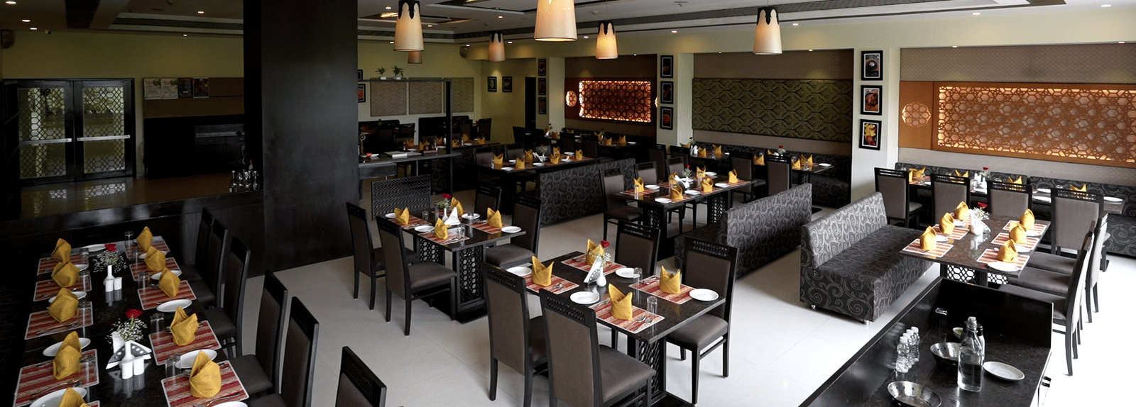 Elegant restaurant with neatly arranged tables and modern decor at Narayani Heights Hotel & Resorts, Ahmedabad.