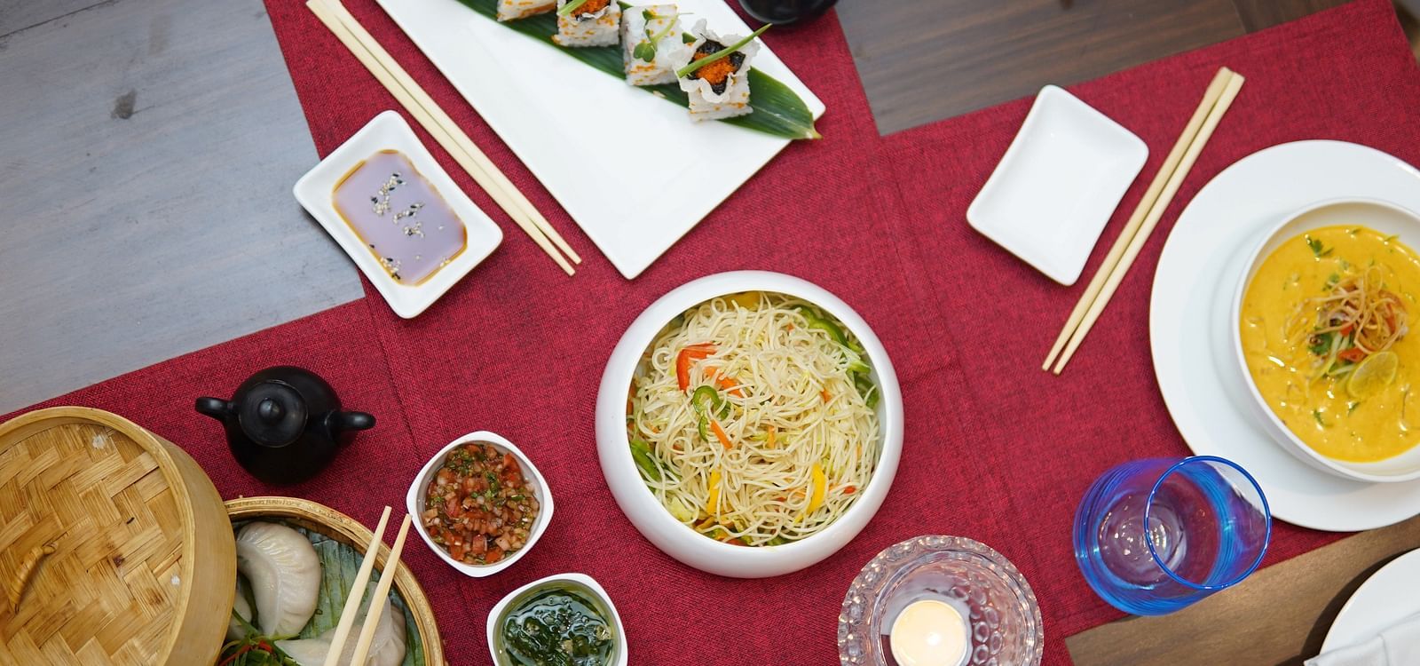 Multiple Asian dishes placed on a table with a red table cloth at Asian Table at Saraca Hotel, Lucknow