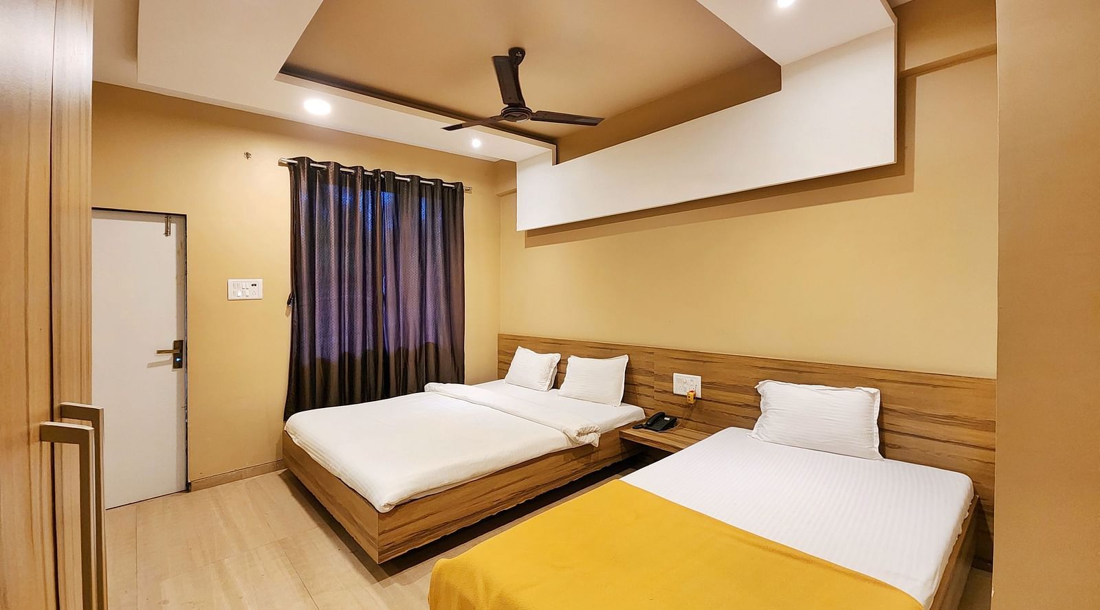 Overview of Triple Premium Room at The Kanila Resort featuring a bed with a gray headboard and white sheets and a window.