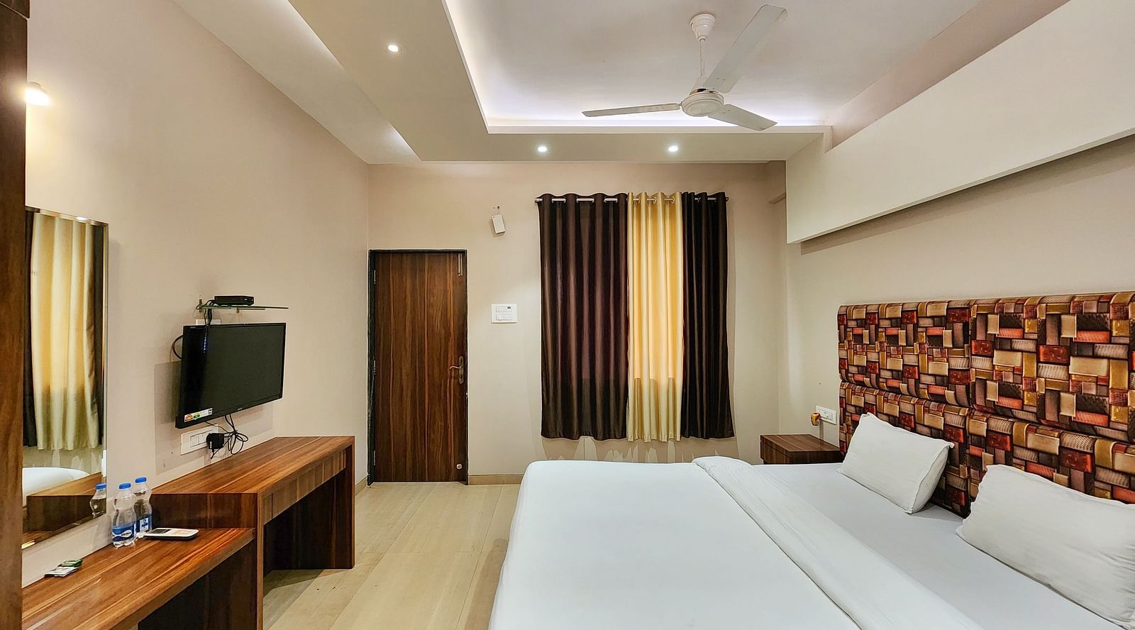 Side view of a Premium Room at The Kanila Resort featuring a bed, a desk, and a wardrobe.