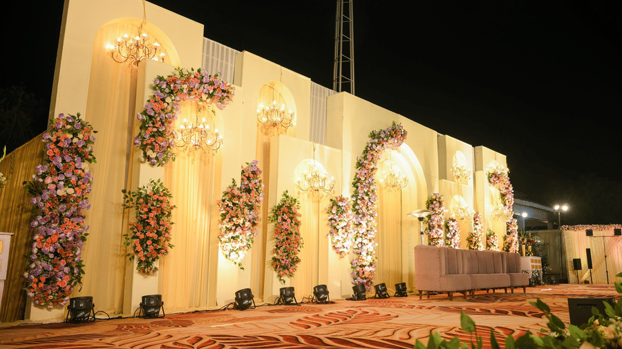 An illuminated decorative façade with arched cut-outs, floral detailing, and a landscaped edge along the front.