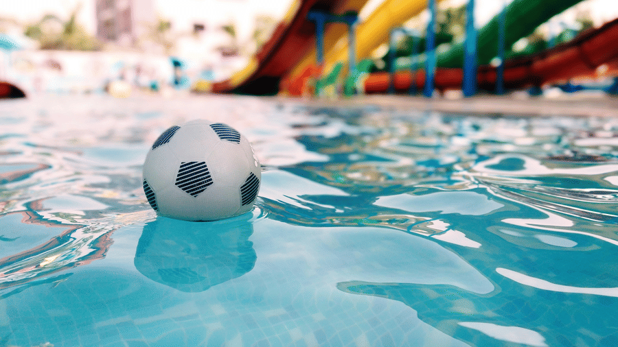 A view from a pool of a small football floating and water slides in the background at Nicco Park in Kolkata