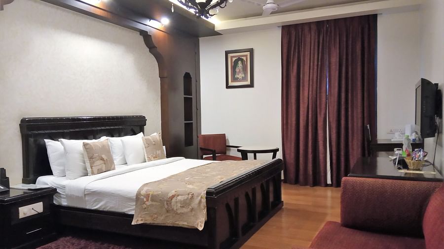 Elegant hotel room at Rockland Hotel, CR Park, featuring classic wooden furniture, chandelier lighting, and warm tones for a luxurious stay.
