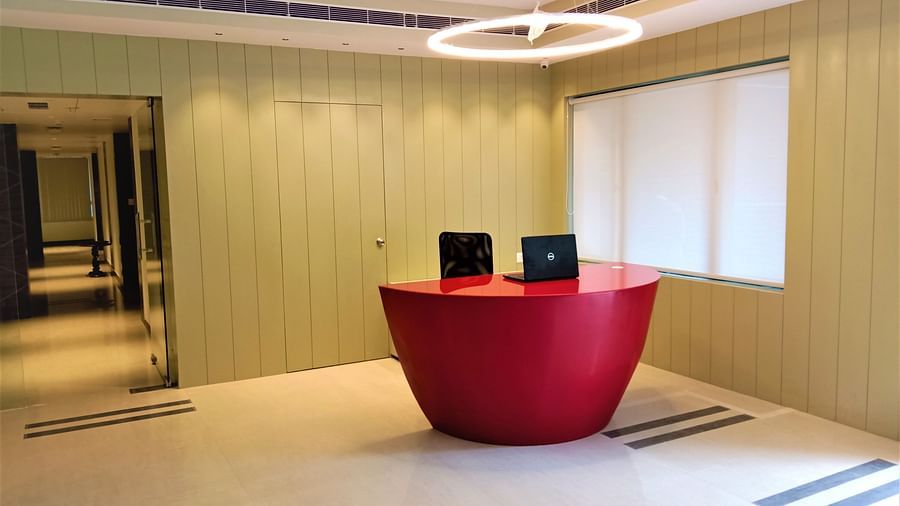 A modern office space with a red half-oval desk and a black office chair in front of a closed window with blinds - Hotel Langford Keys by TGI, Shanti Nagar