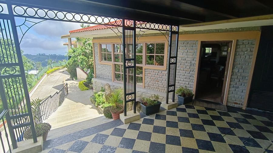 Exterior view of a restaurant with stone walls, surrounded by greenery and a paved path.