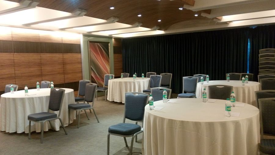 Shot of a meeting hall featuring round tables and black chairs | Mirage Hotel