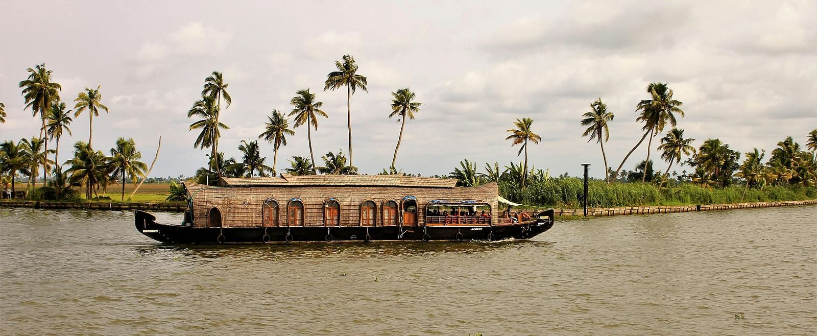 A boat passing by in a lake with trees in the background.