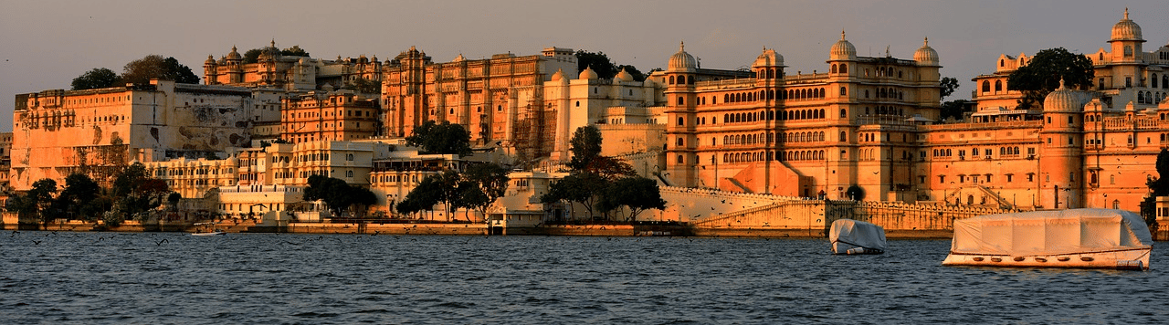 Buildings lined on the shore of a lake under a pale sunset sky.