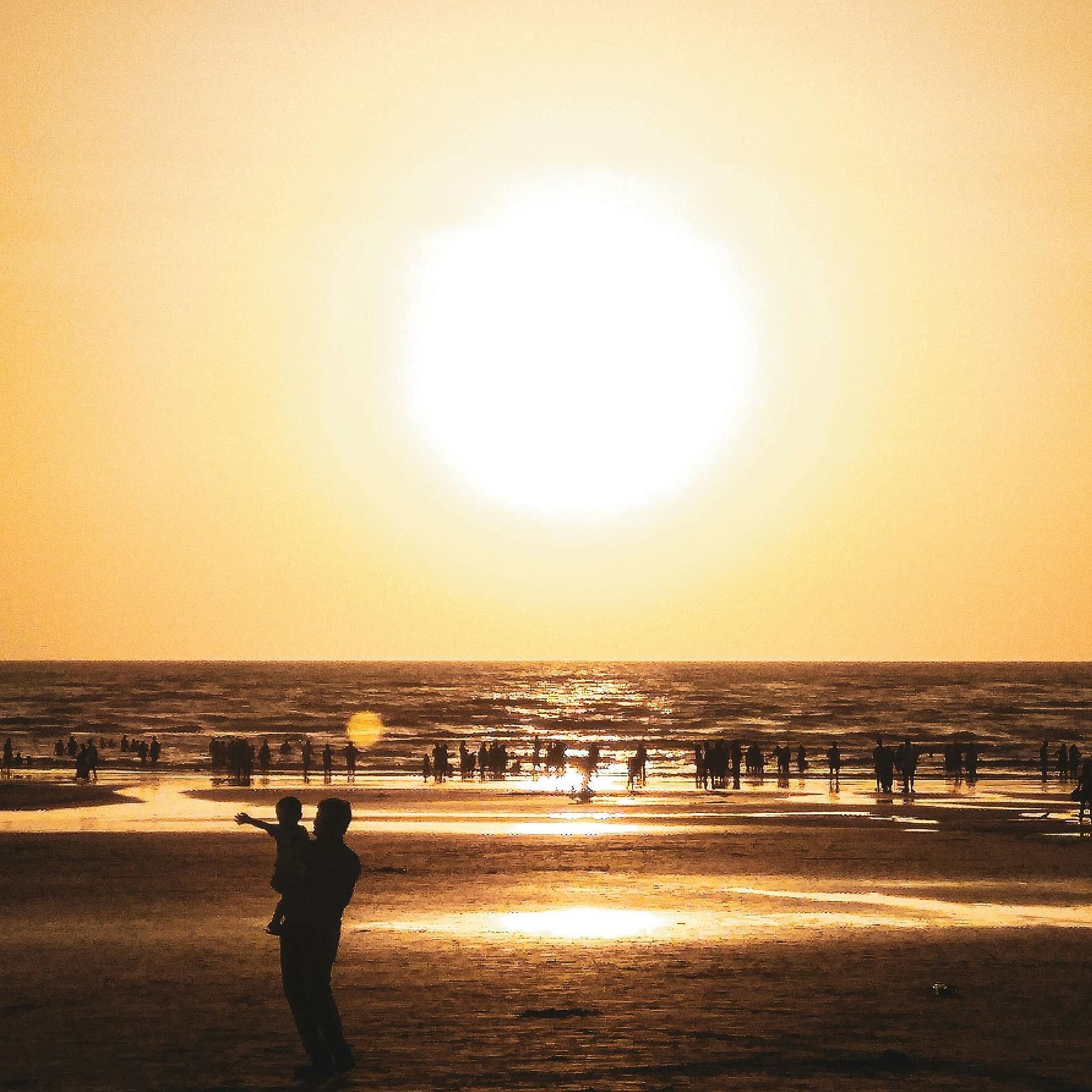 A backlit image of people at a beach at sunset