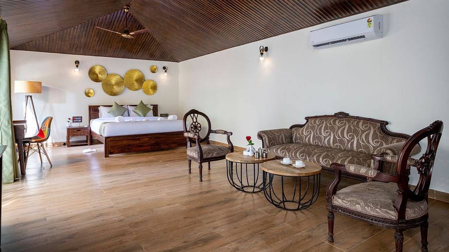 A spacious bed positioned beneath a decorative wallpaper, accompanied by comfortable sofas for relaxation in the room - Stone Wood Nature Resort, Gokarna