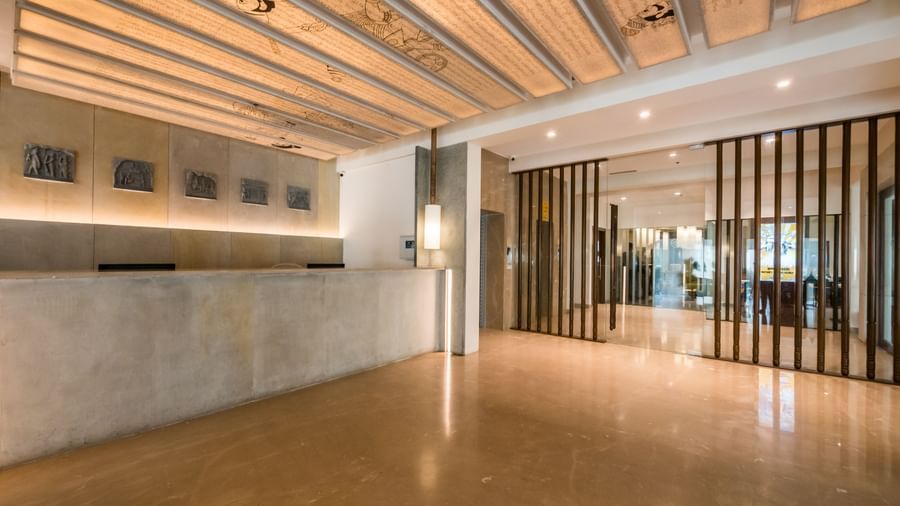 An expansive and bright hotel lobby showcasing several reception stations, unique ceiling designs, and wooden accents, conveying openness at Shilton Dee Cee.
