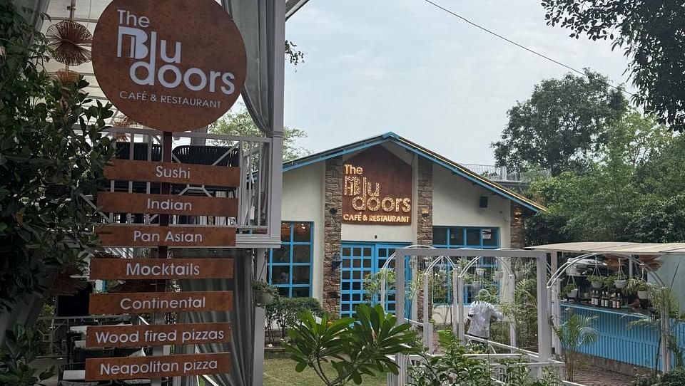 Exterior of 'The Blu Doors Cafe and Restaurant showing a menu sign with various cuisines listed.