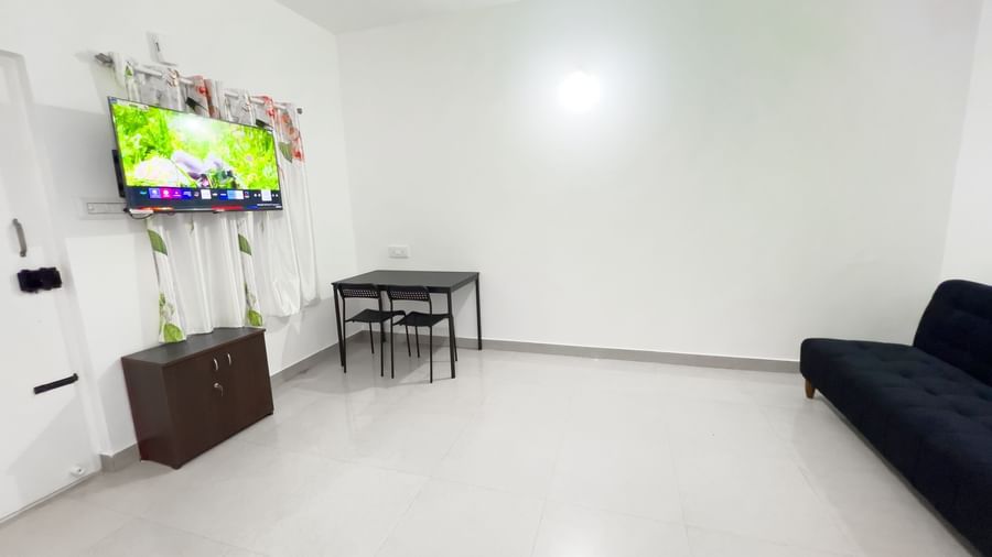 Spacious living area with wall-mounted TV, sofa, and table at The Pinnacle, Electronic City.