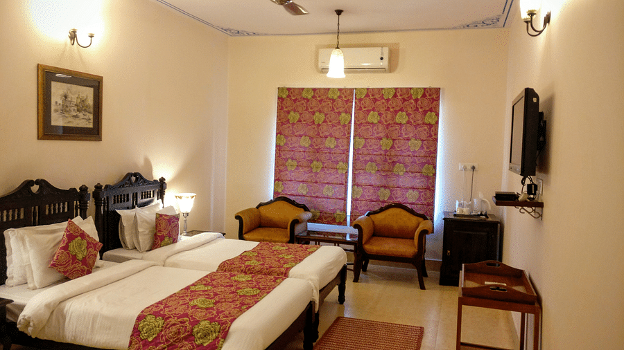 Television and Twin beds with beautiful red bedsheets and red pillow covers at Junior Suite at Suryaa Villa Jaipur