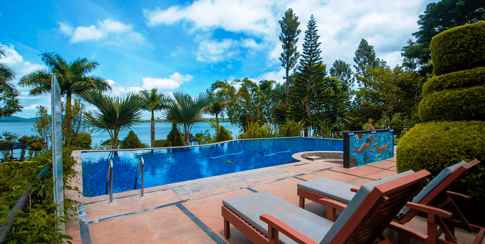 Image of a swimming pool with lounge chairs on the side at Coorg Jungle Camp.