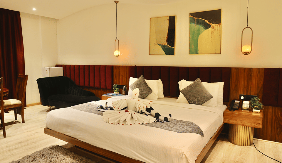Club Suite with a king bed dressed with swan towel art beneath pendant lights and framed artwork