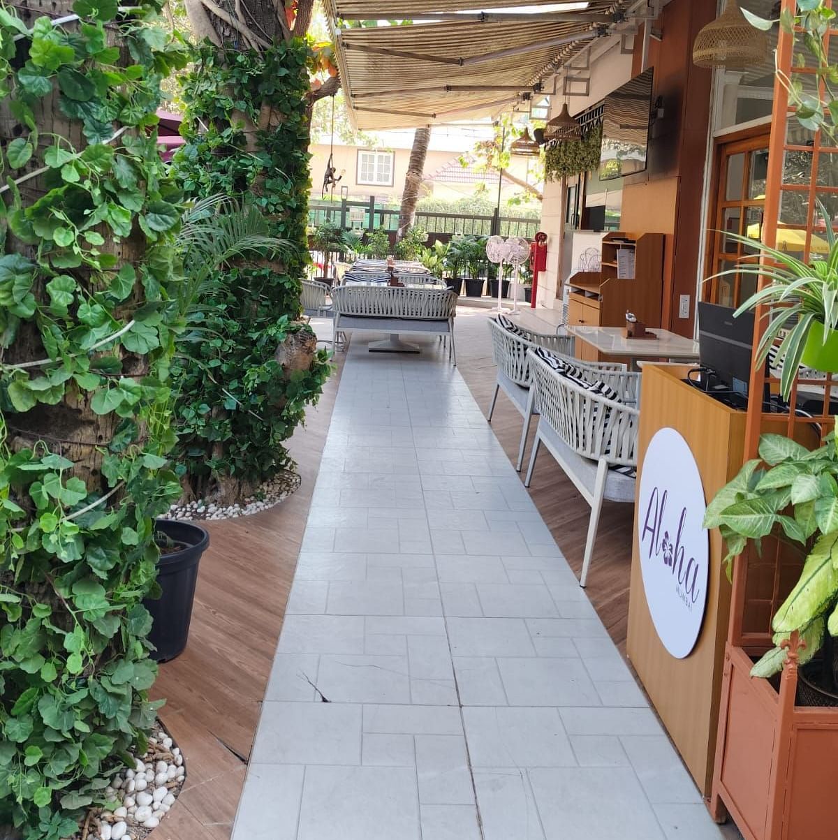 Outdoor seating area at Aloha Mumbai, featuring lush greenery and a cosy ambiance.