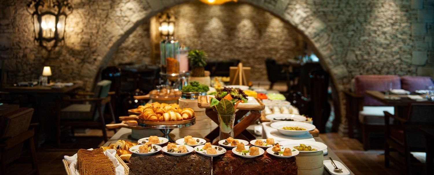 Close-up shot of the buffet table spread with well-plated dishes placed under the warm lighting from the unique chandelier at the Mila restaurant at The Evren, Vagator.