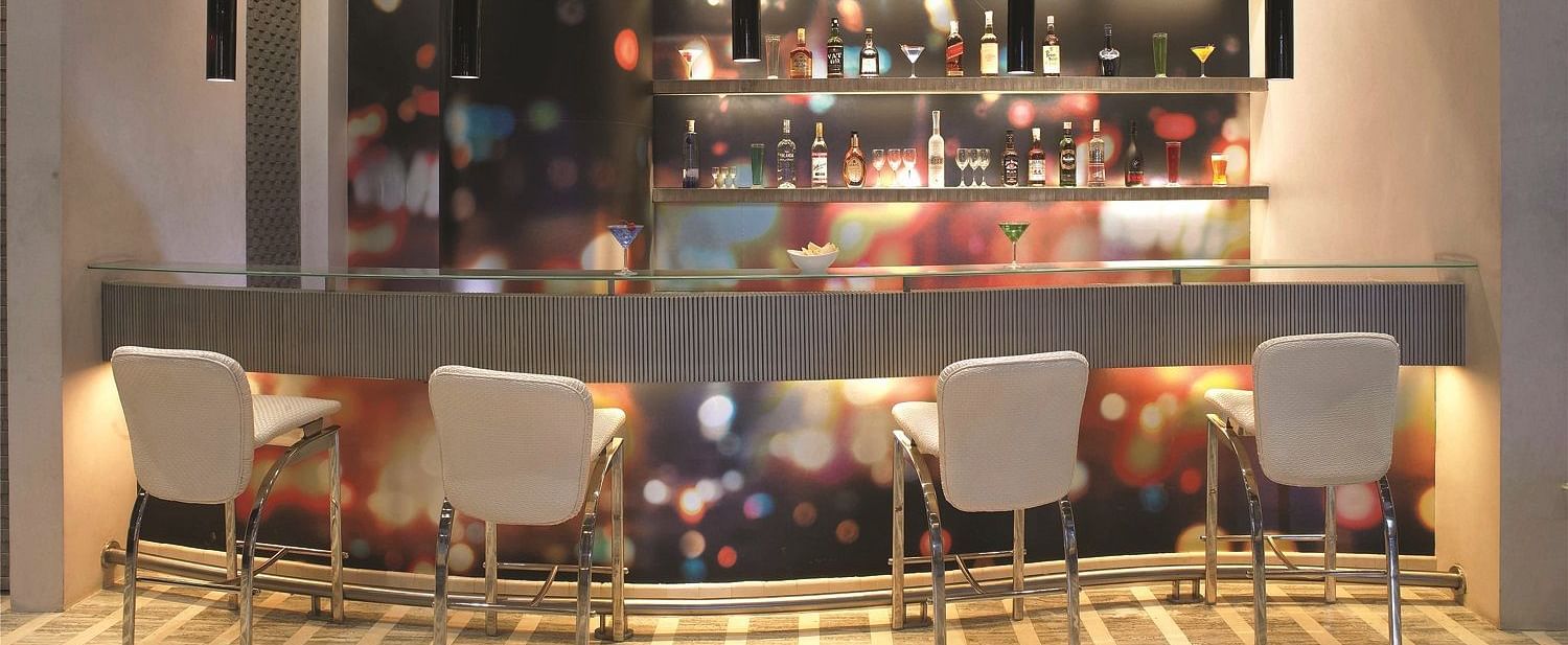 Image of zebra lounge at our hotel featuring a bar stand with chairs and bottles of alcohol | Mirage Hotel