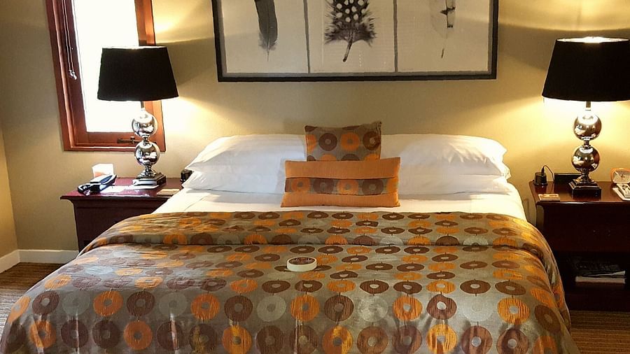 A beautifully designed bed with patterned bedding and warm tones - Brewery Gulch Inn & Spa