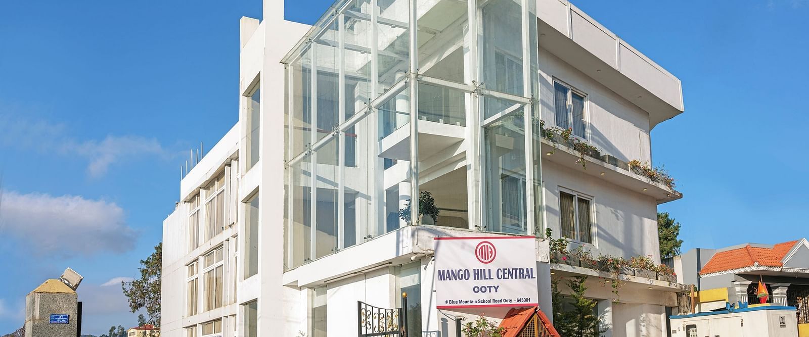 Exterior view of a contemporary white building with glass balconies | Mango HIll Central, Ooty