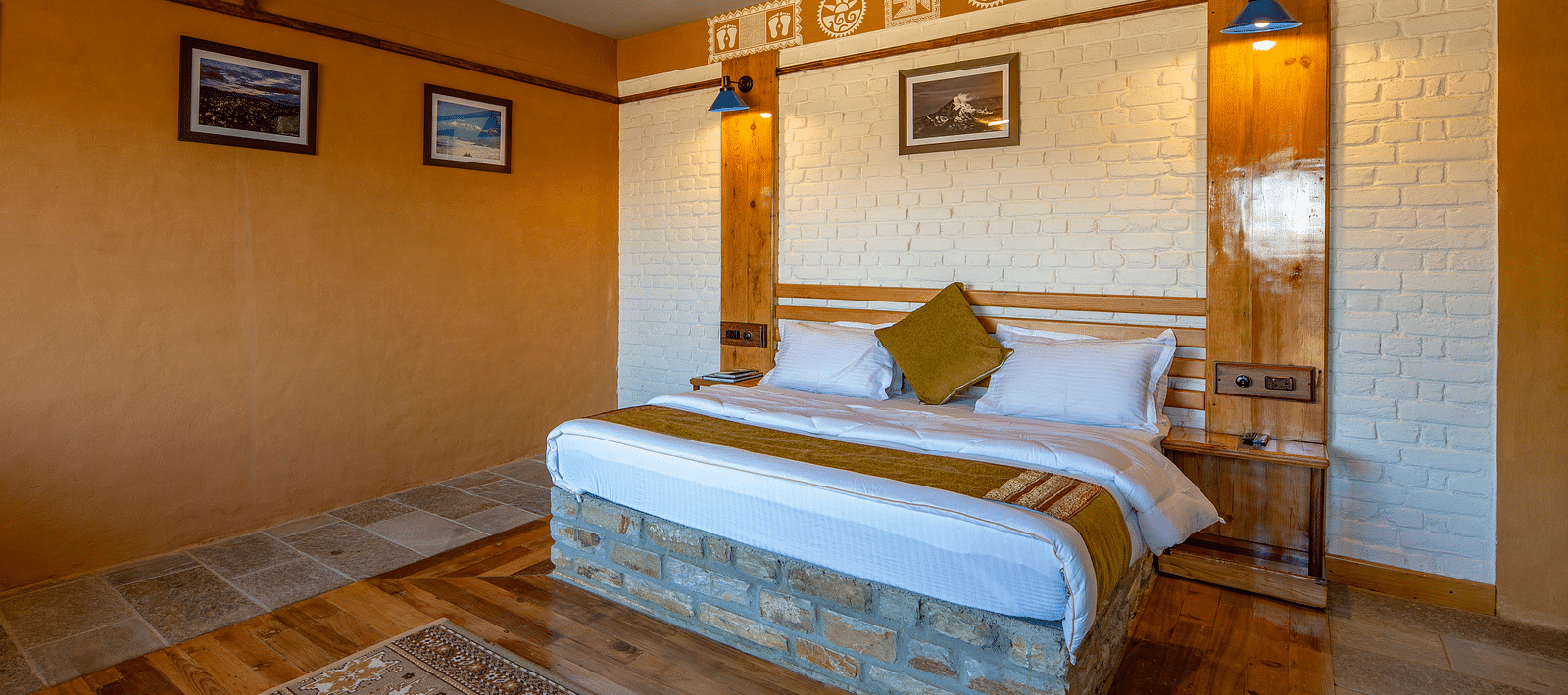 Warm bedroom with wooden flooring, white brickwork, and traditional art above the headboard. - Blusalzz Homes The Himalayan Bungalow, Almora