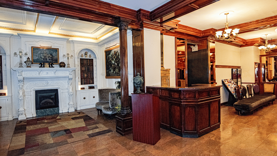 Lobby at Night Hotel Broadway showing lounge seating fireplace decorative columns and warm interior lighting.