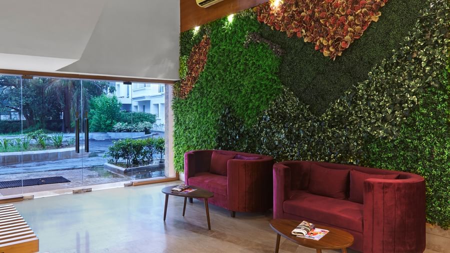 The main entrance and reception area of Monday Hotels Mahape, Navi Mumbai, with a vertical garden and contemporary furniture.