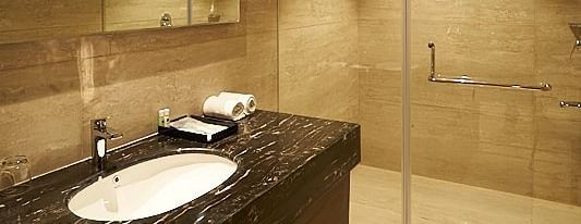 A bathroom with a glass shower enclosure, sink, mirror, and towel rack at The Hamuse Hotel, Kodaikanal.