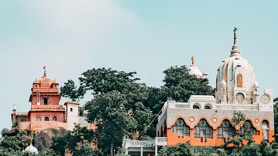 Distant view of a temple complex surrounded by trees and open sky.