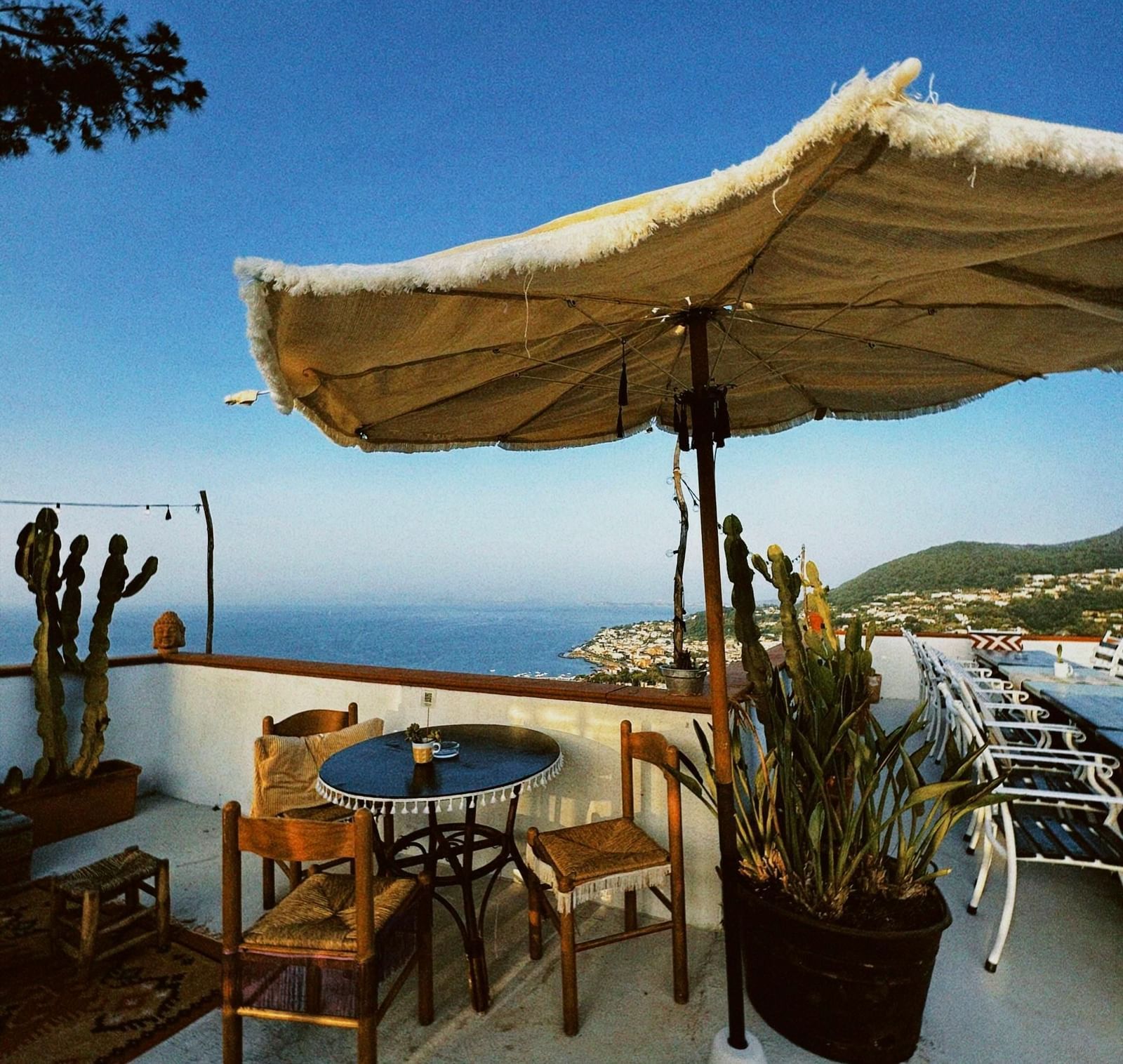 An outdoor dining area with a huge umbrella over it overlooking the ocean views.