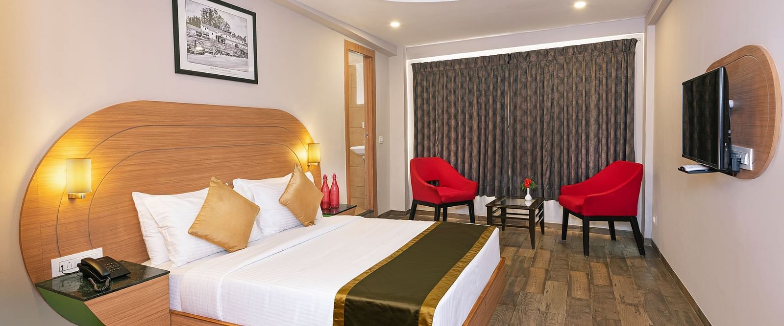 An image of a bedrom with dube sized bed and chairs on a different corner  | Mango HIll Central, Ooty