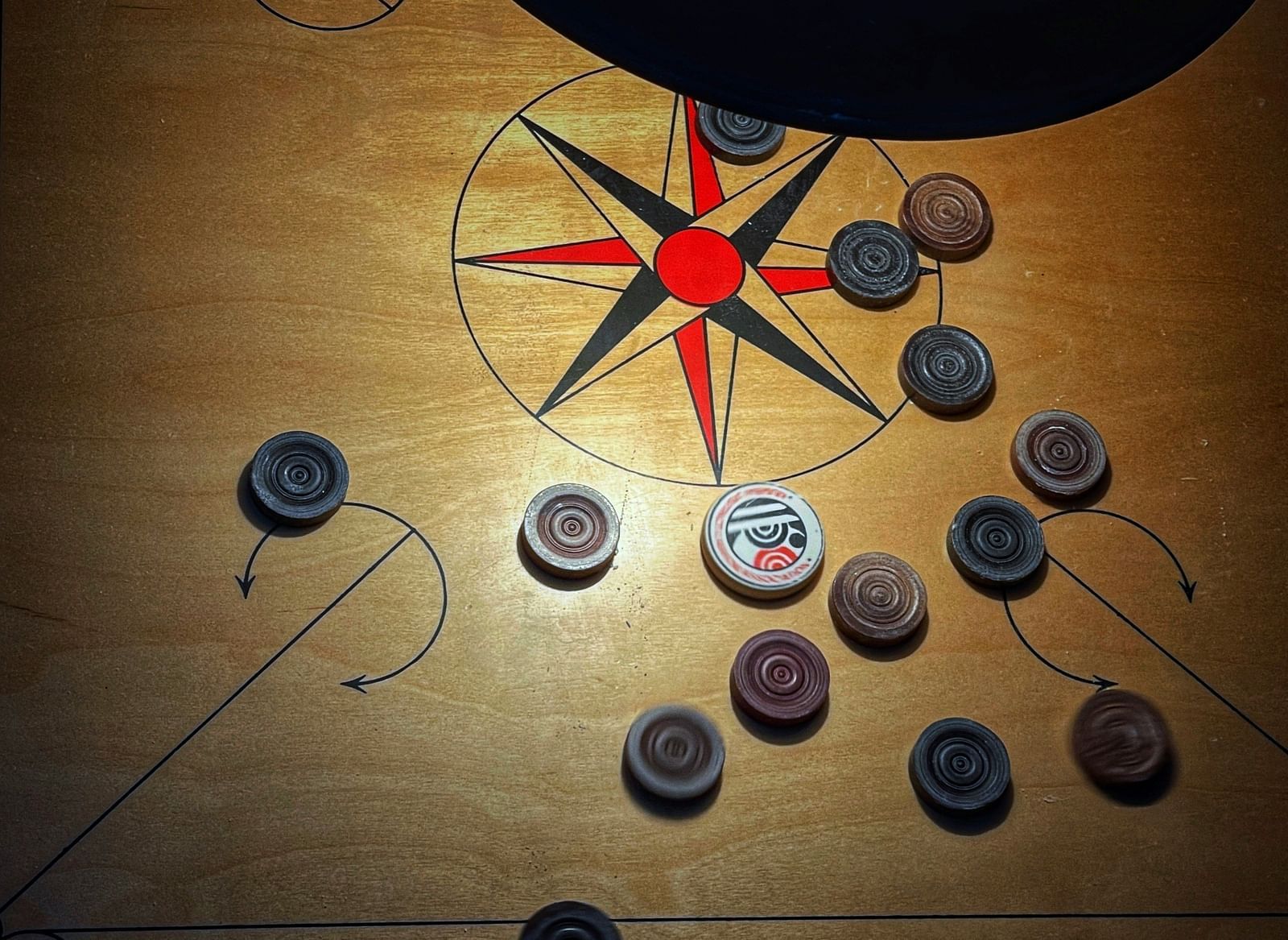 A carrom board with arranged coins and a striker, ready for a game.