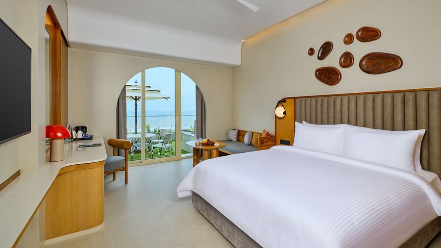Image of the Premium Room at Swosti Premium Beach Resorts in Puri featuring a plush bed and a TV next to which a work desk is placed beside the way to the balcony