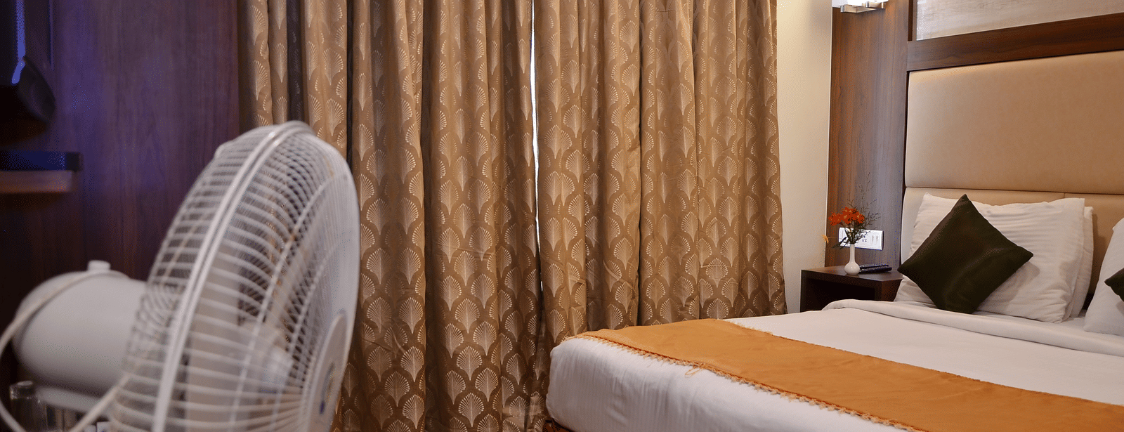 A neatly designed room with a single bed, curtain backdrop, and pedestal fan for added comfort - Benzz Park, Kodaikanal