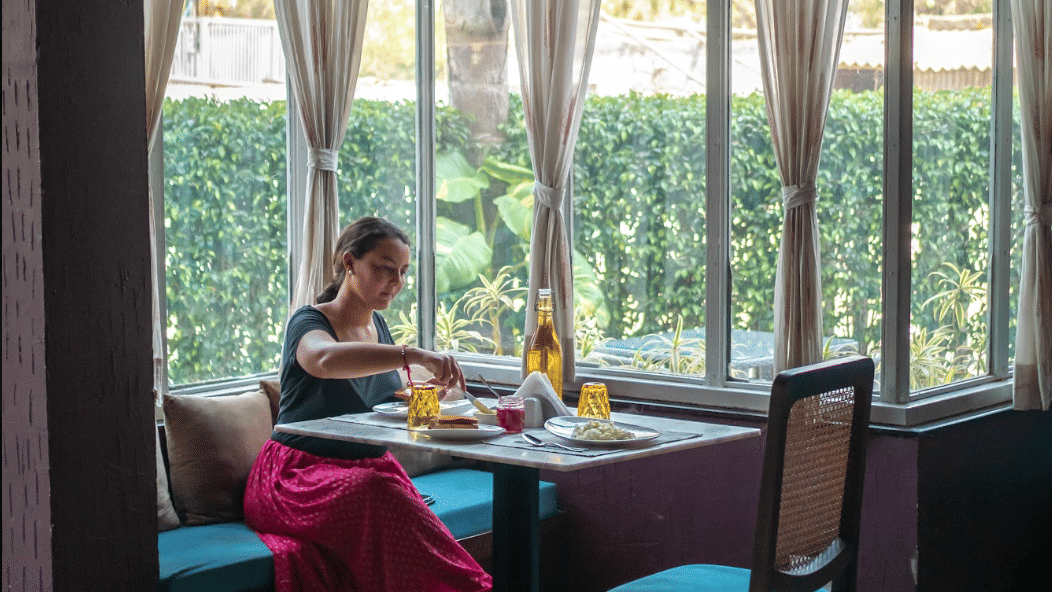 Guest enjoying a meal seated at a cosy window table inside the restaurant area.